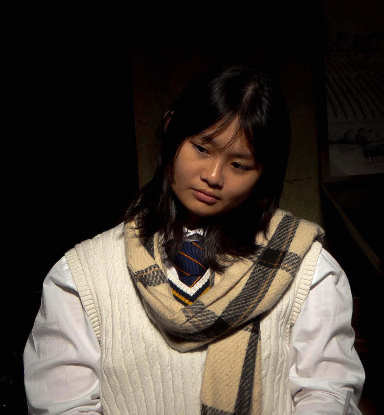 A picture of Alexis looking wistful with dramatic lighting and dark background.